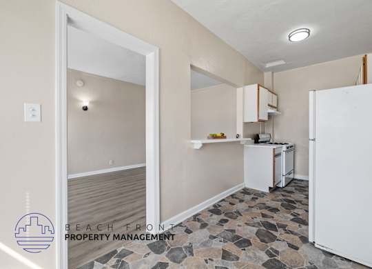 A kitchen with a white refrigerator and a stone floor.
