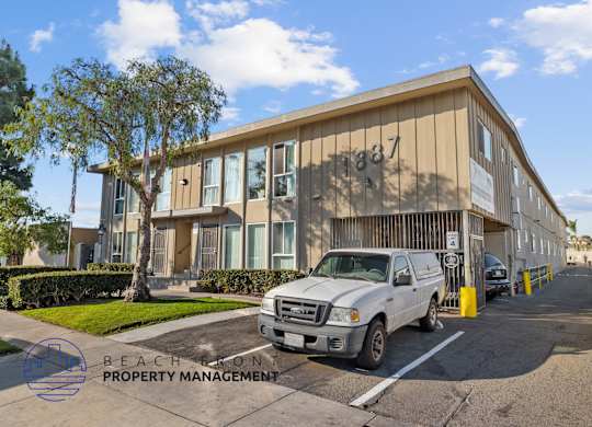 A white truck is parked in front of a building with the number 1837 on it.