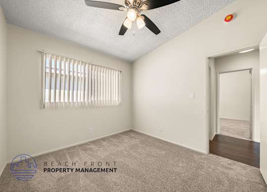 A room with a ceiling fan and a window with blinds.