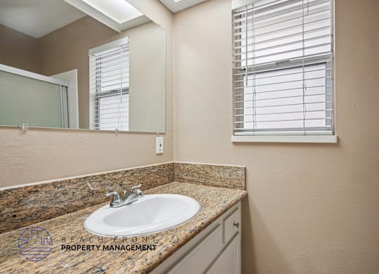 A bathroom with a granite countertop and a large mirror.
