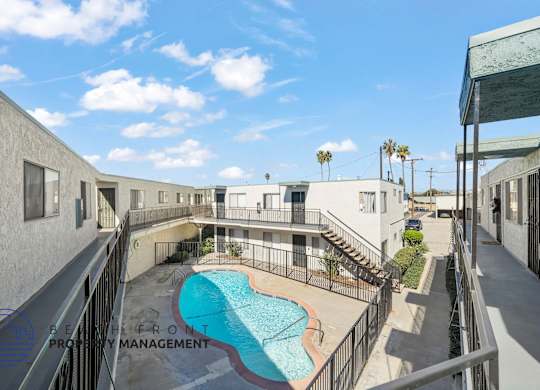 A pool is surrounded by a fence and a building.