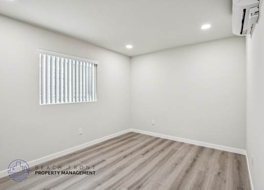 A room with a window and wooden flooring.