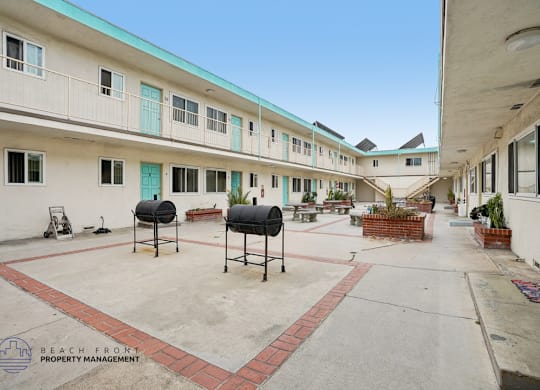 A courtyard with a red brick border and a white building with blue trim.