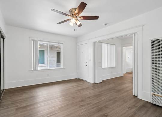 A room with a ceiling fan and wooden flooring.