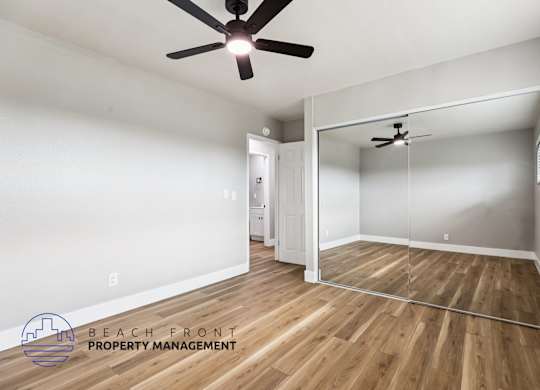 A room with a ceiling fan and wooden flooring.