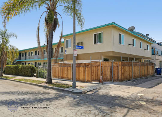 A building with a blue sign on the front is surrounded by a wooden fence.