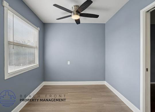 A room with a ceiling fan and a window with blinds.