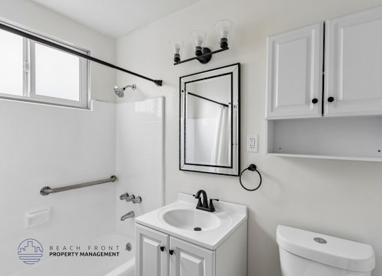 A bathroom with a sink, toilet, and mirror.