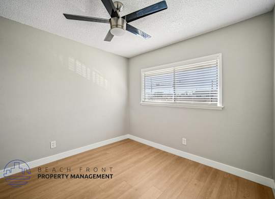 A room with a ceiling fan and a window with blinds.