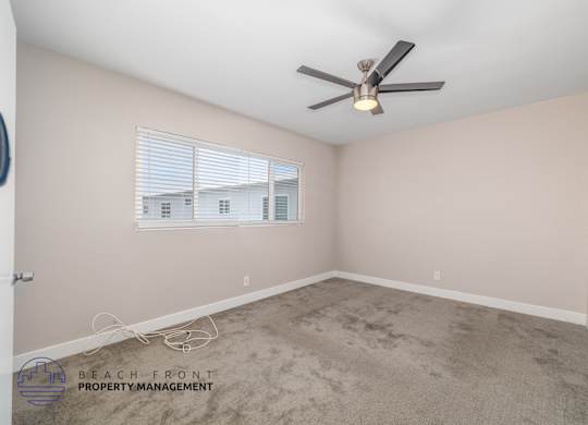 A room with a ceiling fan and a window with blinds.