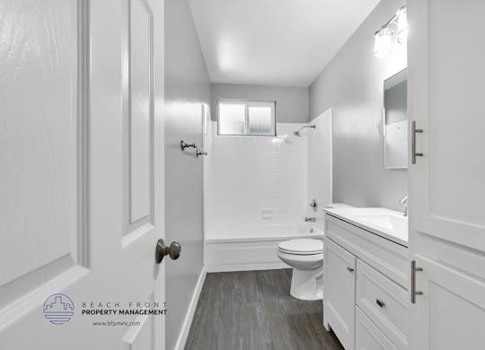 A white bathroom with a toilet, sink, and mirror.