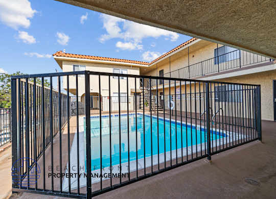 a swimming pool behind a wrought iron fence in front of a house