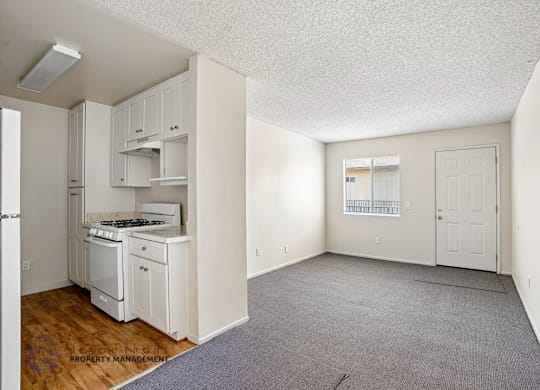 A small, empty room with a kitchenette and a door leading to another room.