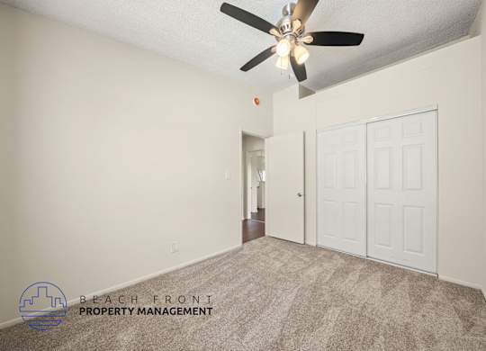 A room with a carpet floor and a ceiling fan.