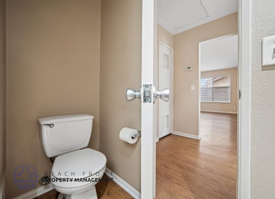 A bathroom with a toilet and a door leading to another room.