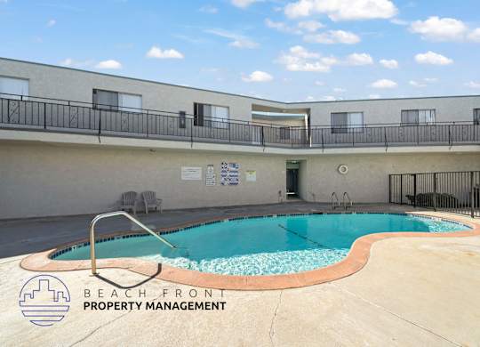 A pool with a slide and a sign that says Beach Front Property Management.