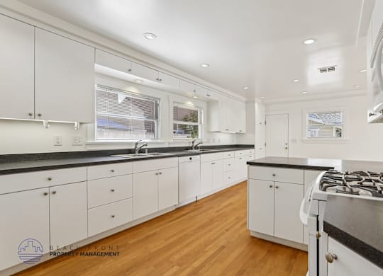 A modern kitchen with white cabinets and a black countertop.