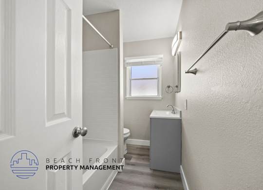 A bathroom with a toilet, sink, and a window.