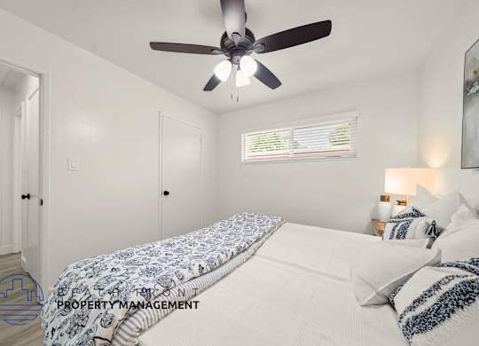 A bedroom with a bed, pillows, and a ceiling fan.