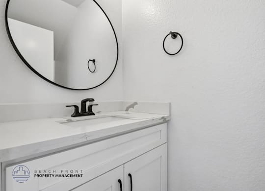 A bathroom sink with a round mirror above it.