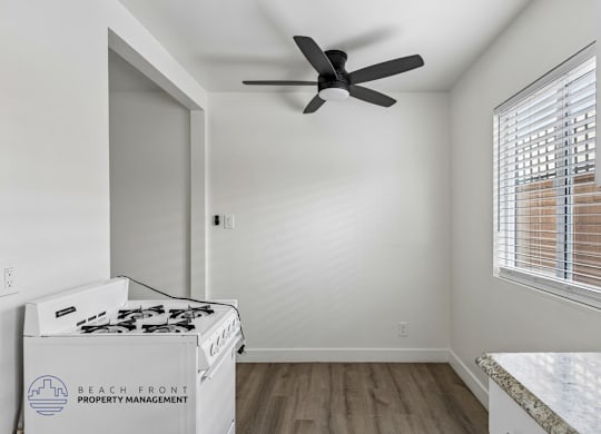 A room with a fan and a stove top oven.