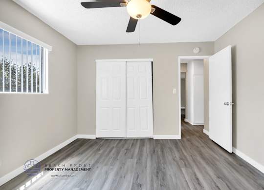 A room with a ceiling fan and a window with blinds.