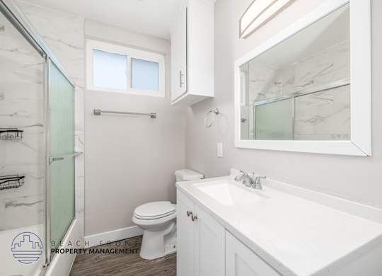A white bathroom with a toilet, sink, and mirror.