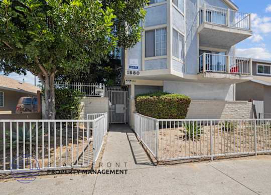 A modern two-story house with a white fence in front.
