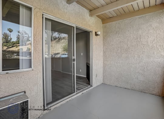 A patio area with a sliding glass door and a wall with a textured finish.