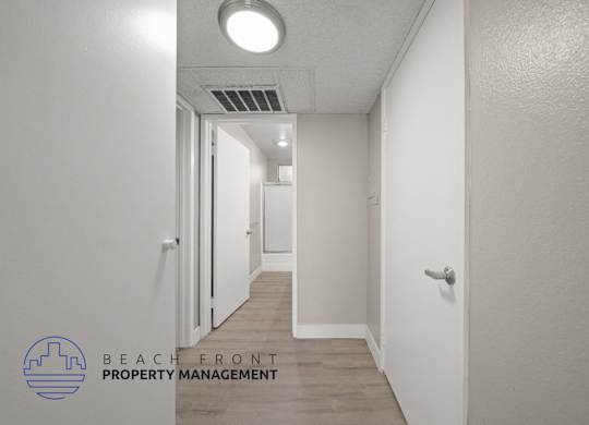 a renovated hallway with white walls and wood flooring and a door to a closet