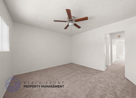 A room with a ceiling fan and carpeted floor.