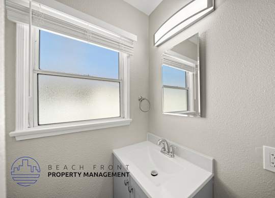 A bathroom with a large window and a white sink.