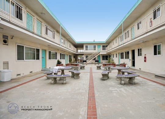 A courtyard with tables and benches surrounded by buildings.