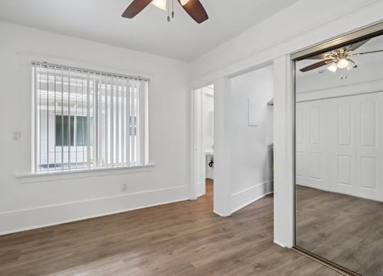 A room with a ceiling fan and a window with blinds.
