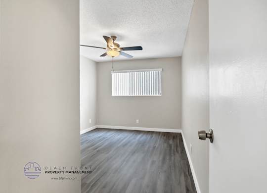 A room with a ceiling fan and a window with blinds.