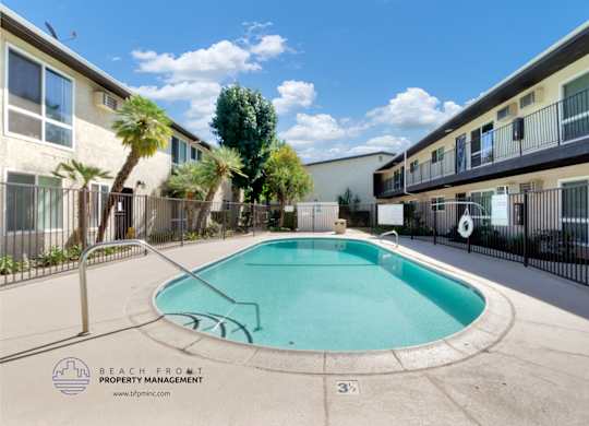 A pool surrounded by a fence and apartment buildings.