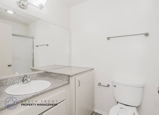A white toilet sits next to a white sink in a small bathroom.