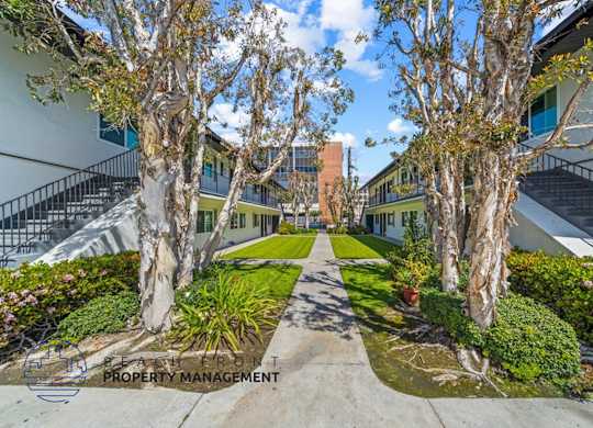 a courtyard between two buildings with trees and grass