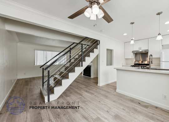 A spacious room with a staircase and a kitchen area.