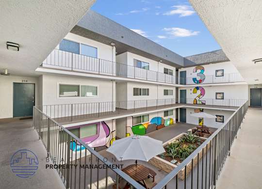 A courtyard with a white fence and a white umbrella.