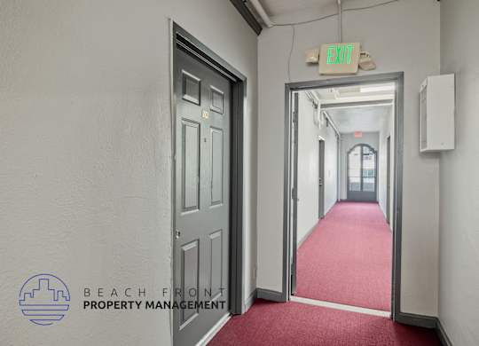 A hallway with a red carpet and a green exit sign.
