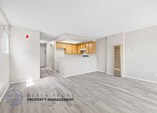 A spacious room with wooden flooring and a logo for Beach Front Property Management.