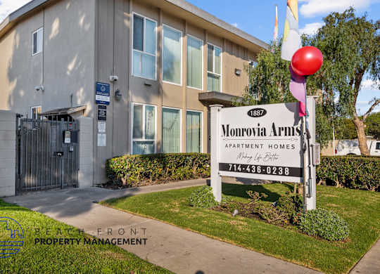 A sign for Monrovia Arms Apartment Homes is in front of a building.