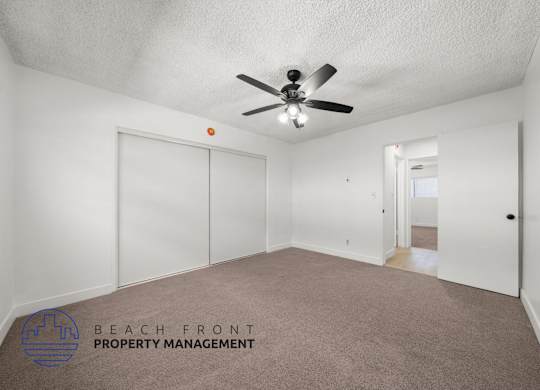 A spacious room with a ceiling fan and carpeted floor.