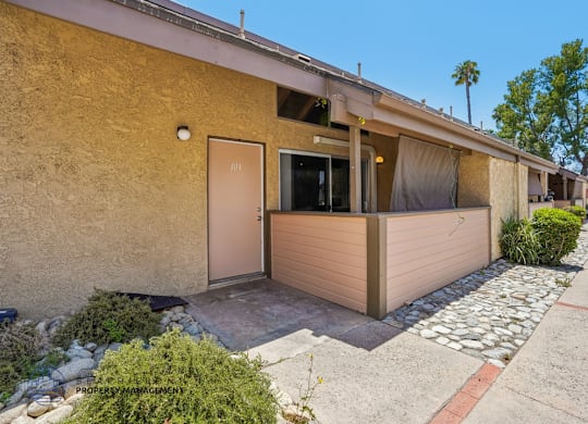 A beige building with a brown door and windows.