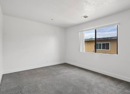 A room with a window and a view of a building outside.