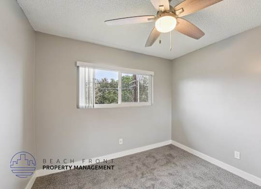 A room with a ceiling fan and a window with blinds.