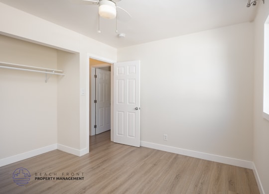A room with a door and a window with a white wall.