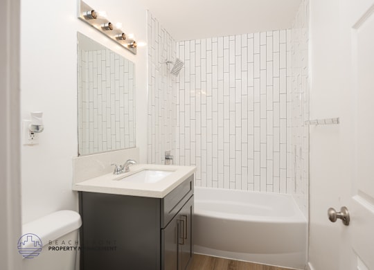 A white bathroom with a black cabinet and a white sink.