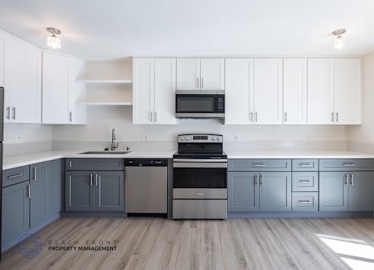 A kitchen with white cabinets and a wooden floor.